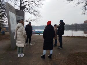 People standing next to Dutzendteich looking at a n information board.